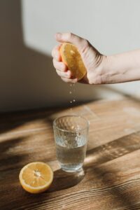 a person squeezing a lemon in a glass of water